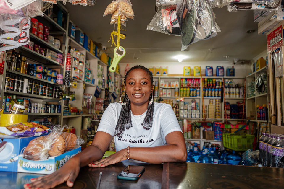 A shopkeeper behind the counter of a well-stocked general store