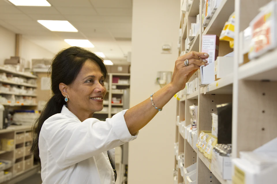 A pharmacist taking a box from a dispensary shelf